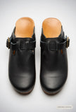 Top view of black closed-toe buckle clogs with open backs and tan footbeds